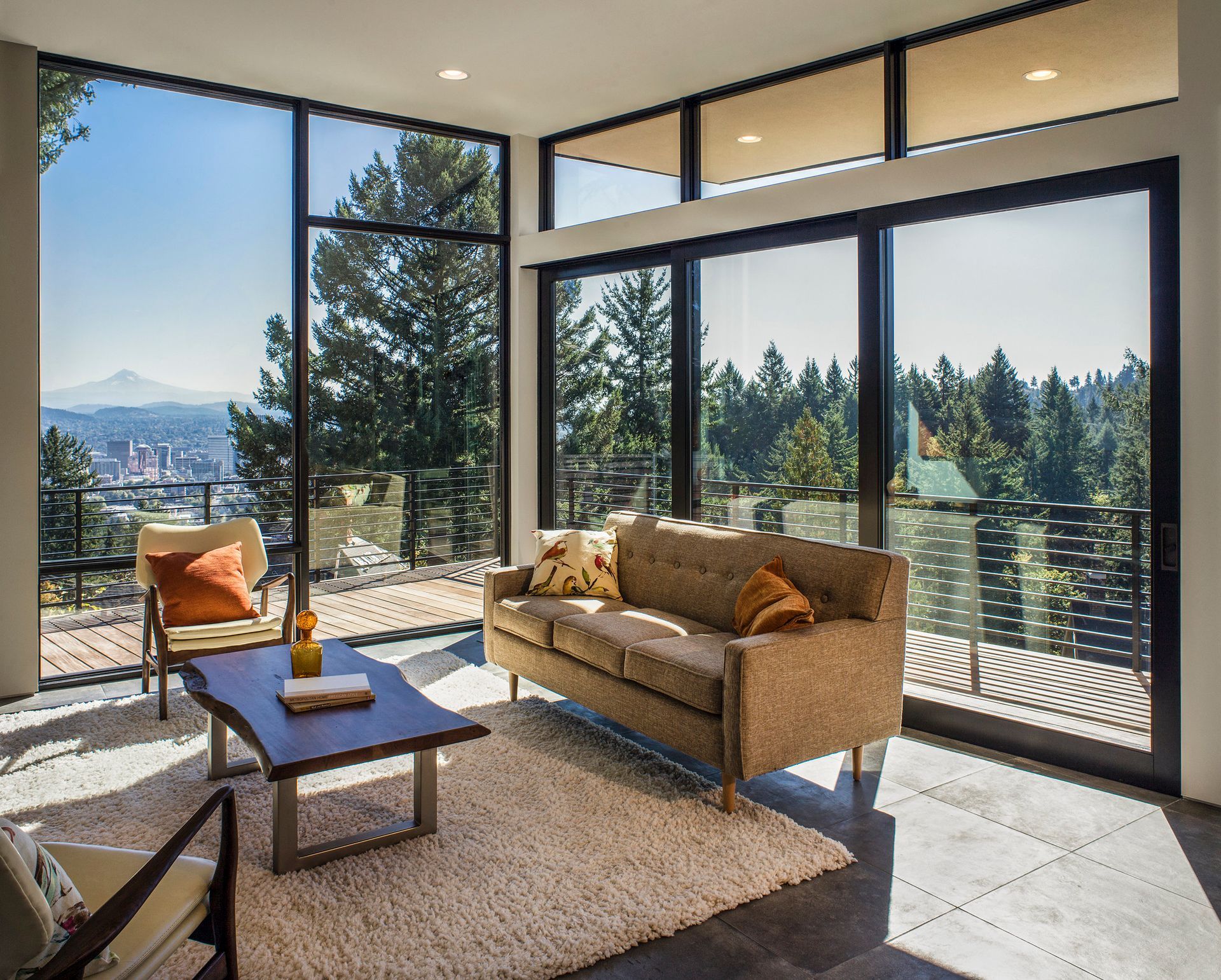 A living room with a couch , coffee table , chairs and lots of windows.