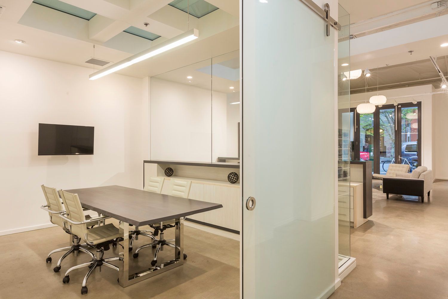 A conference room with a table and chairs and a sliding glass door.