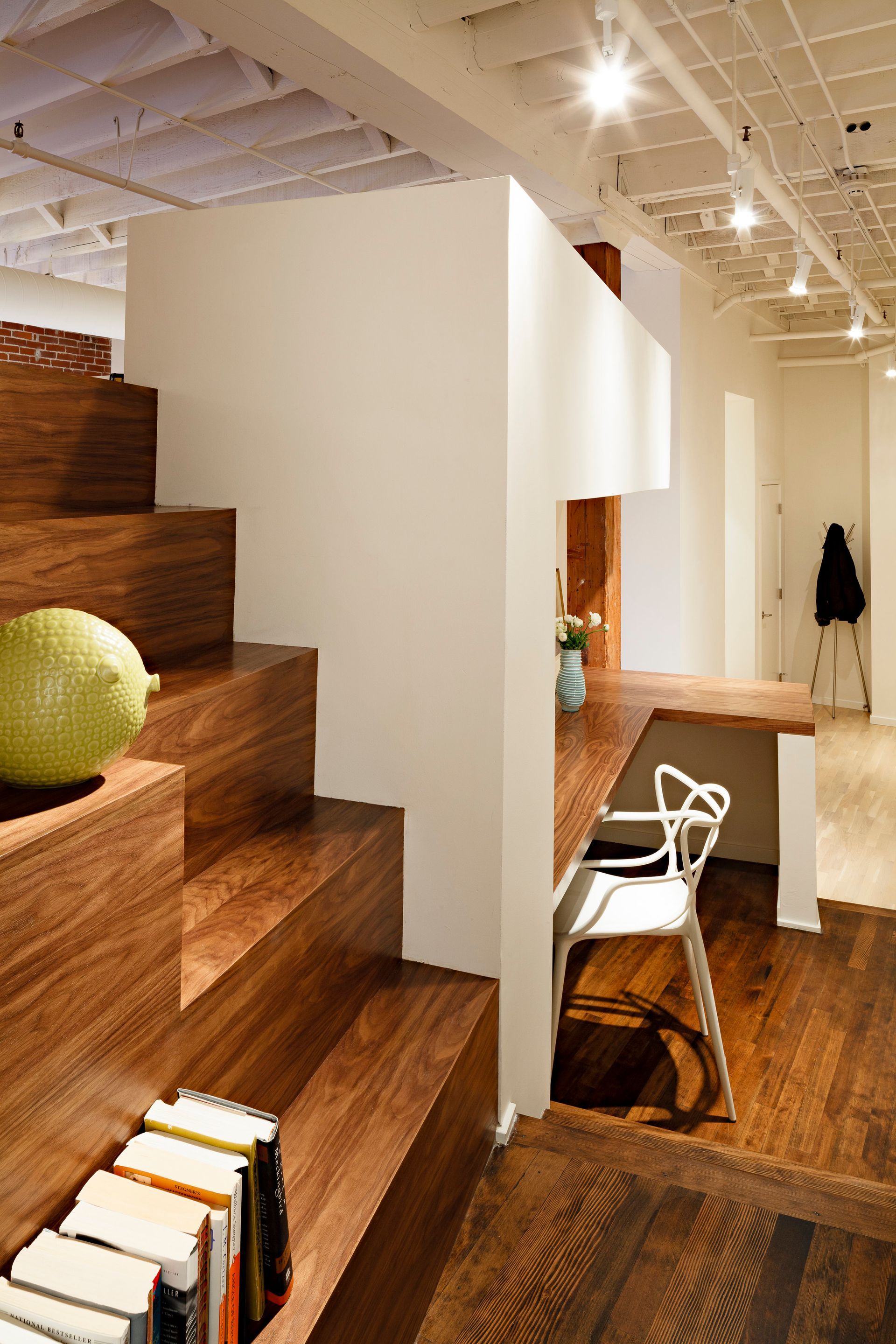 A wooden staircase leads up to a desk and chair