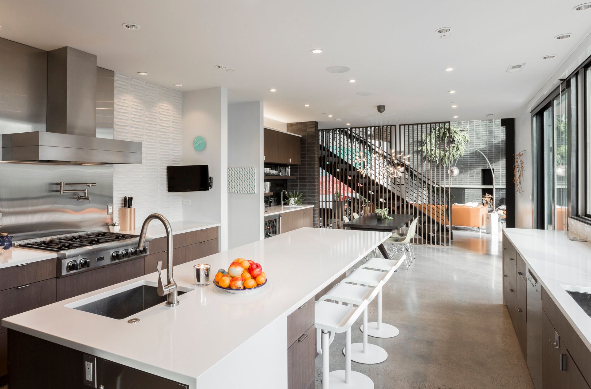 A kitchen with a large island , sink , stove and stairs.