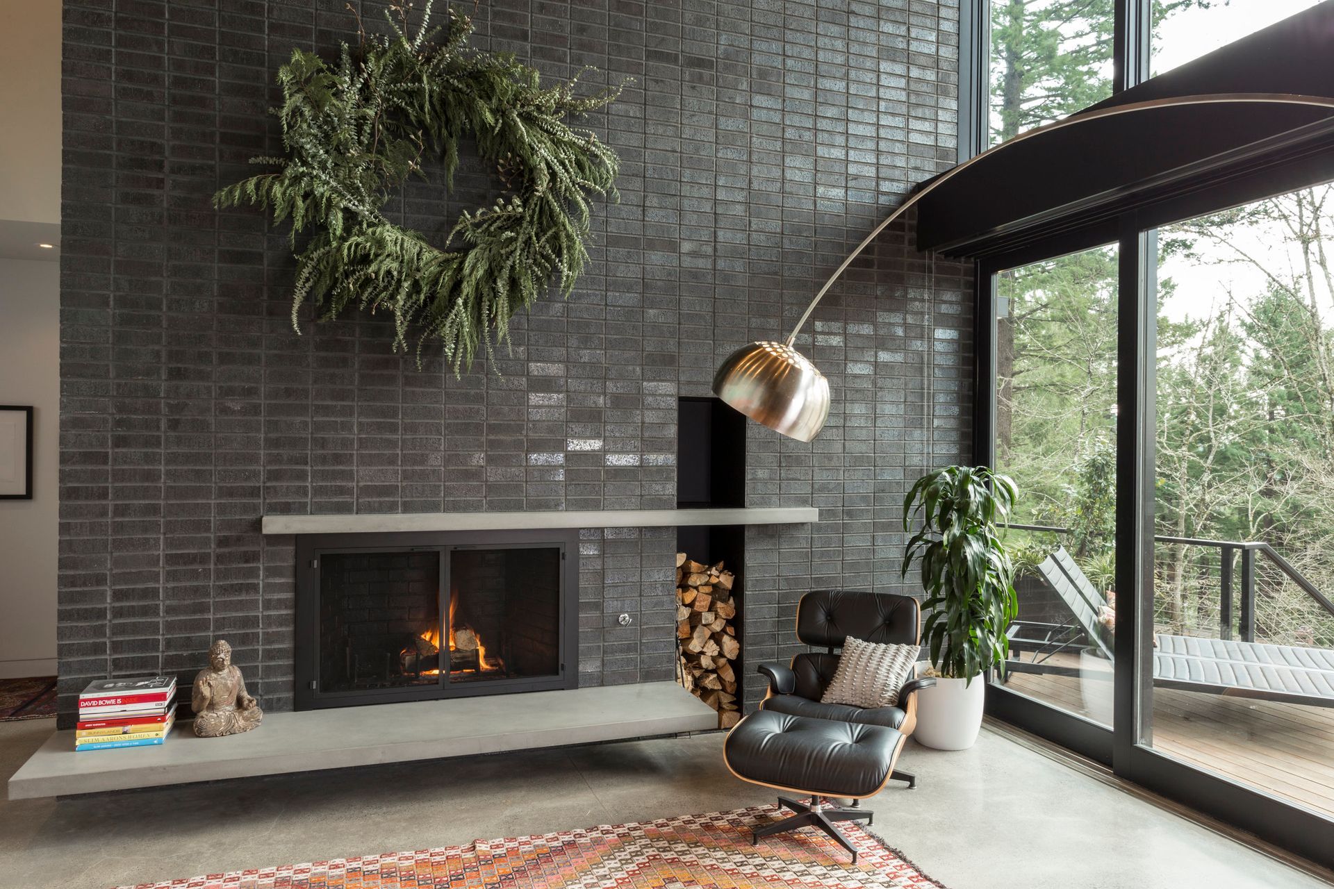 A living room with a fireplace , chair , rug and a lamp.