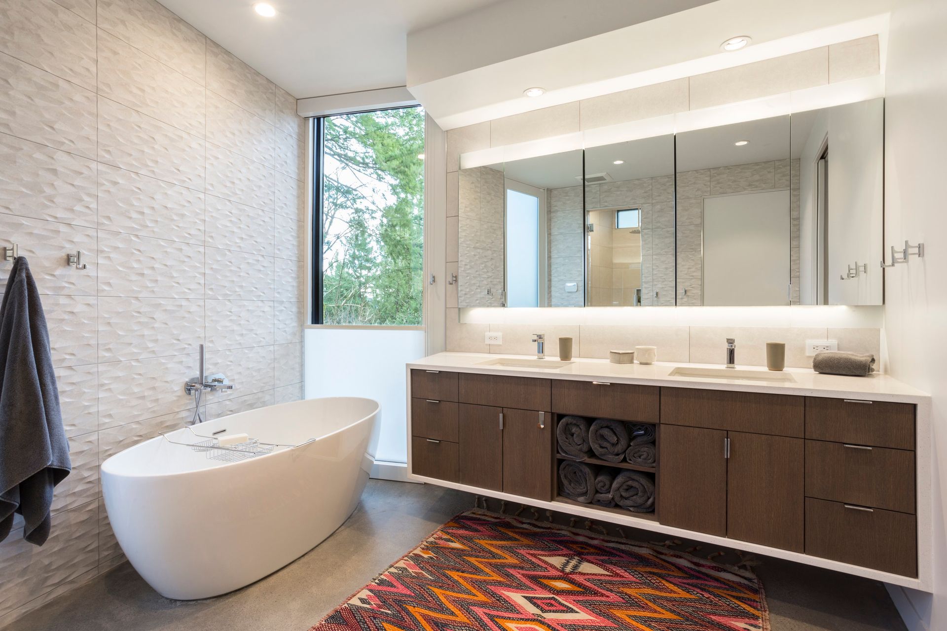 A bathroom with a bathtub , sinks , mirrors and a rug.
