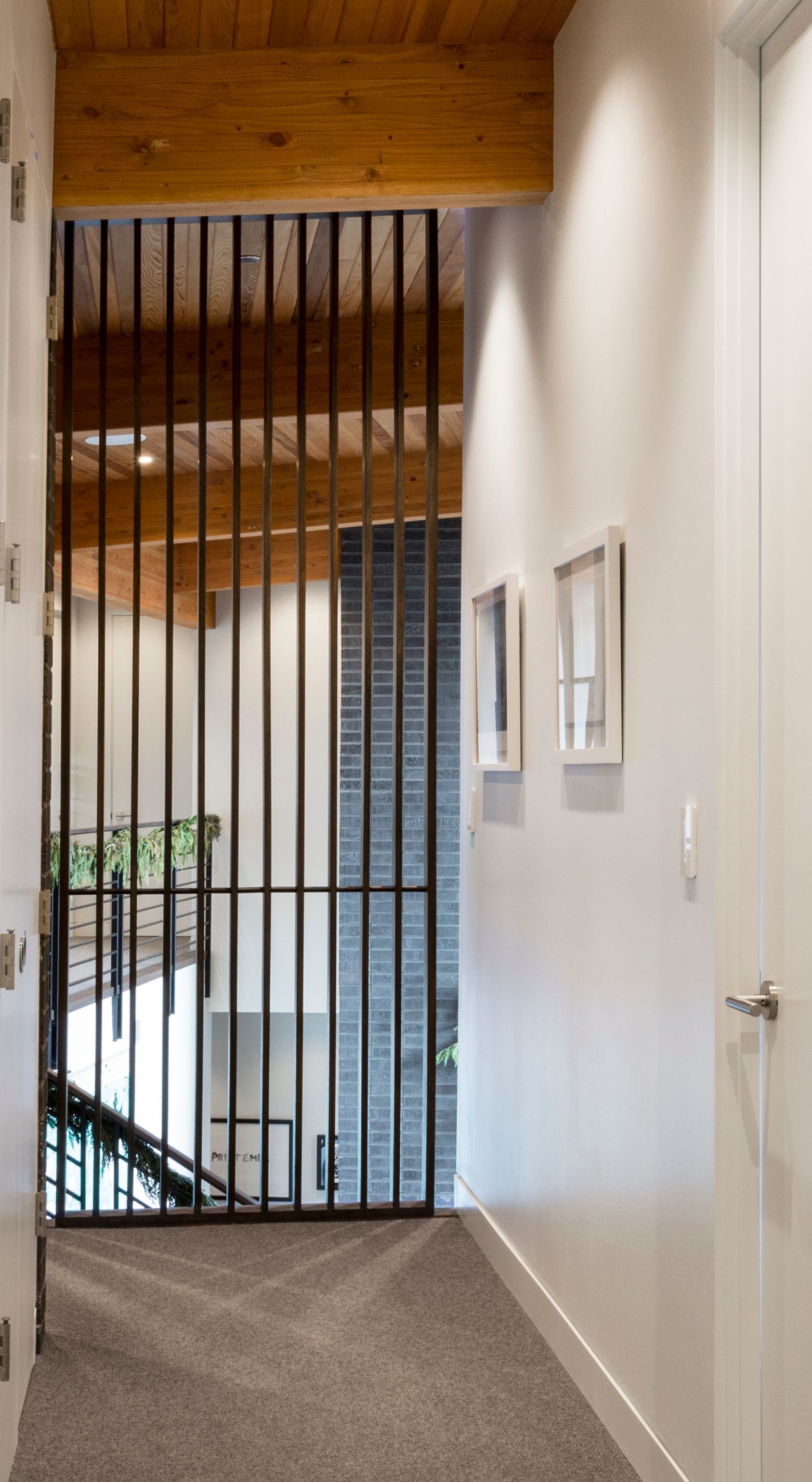 A hallway with a railing and a staircase in the background.