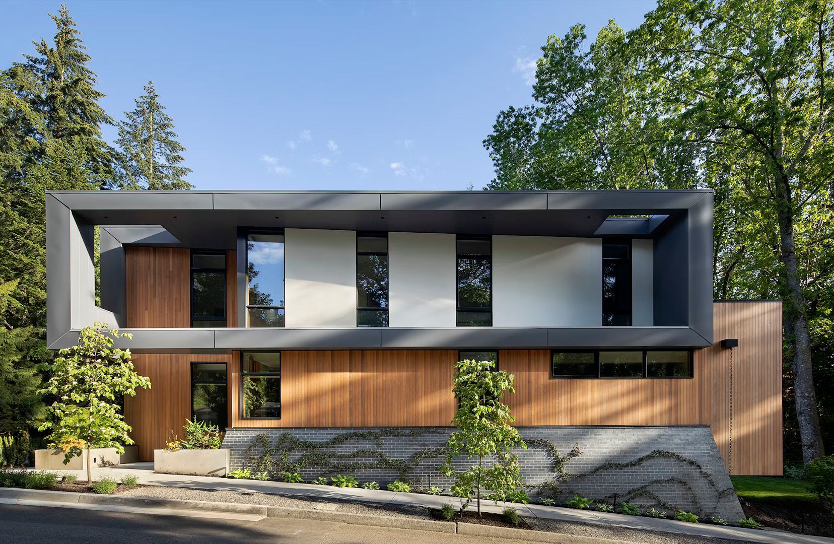 A modern house with a wooden facade is surrounded by trees.