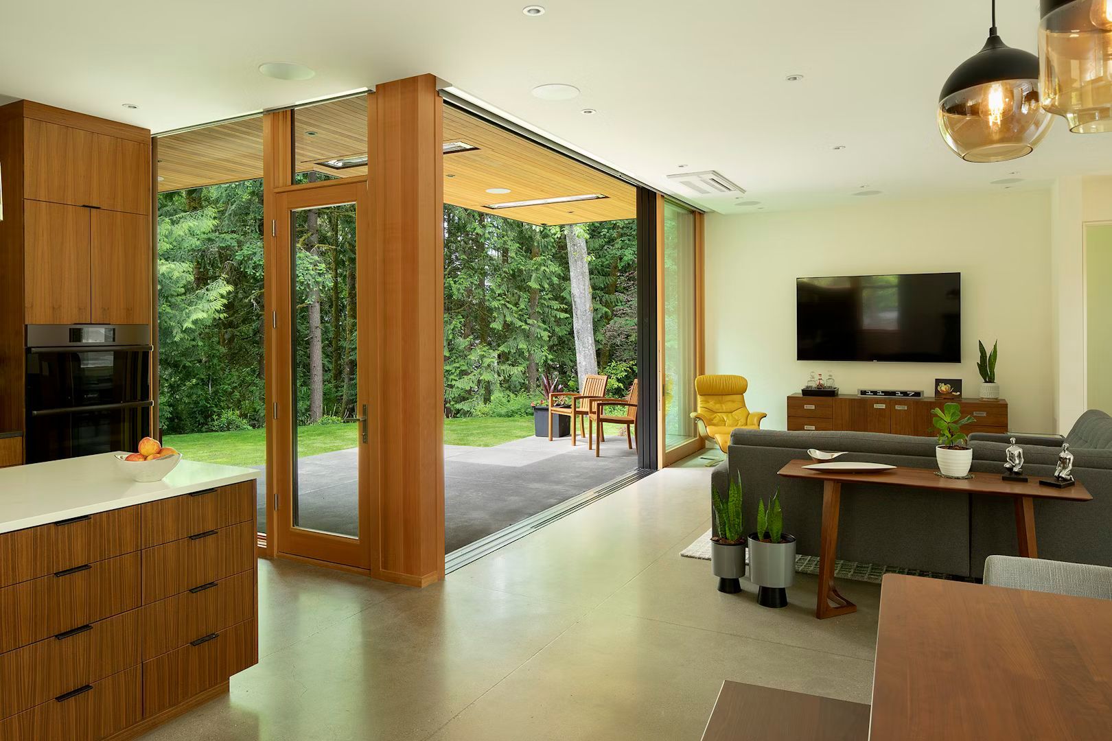 A living room with a couch , table , television and sliding glass doors leading to a patio.