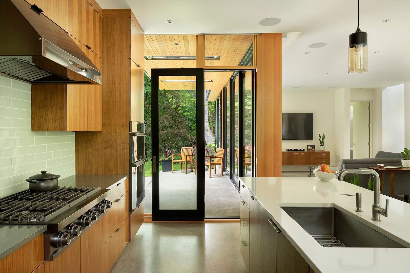 A kitchen with a stove, sink, and sliding glass doors leading to a patio.