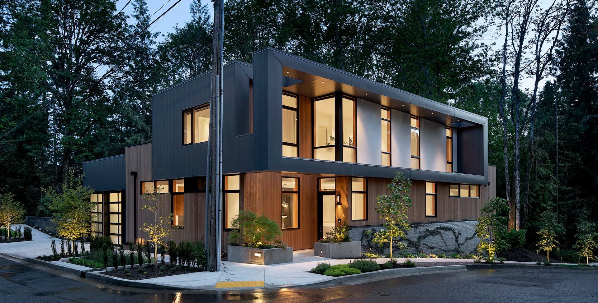 A modern house with a lot of windows is surrounded by trees.