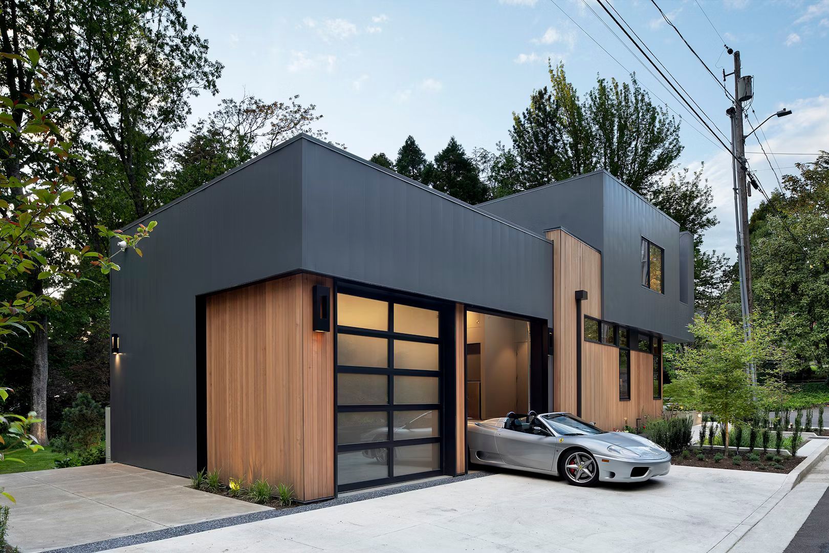 A car is parked in front of a modern house with a garage.