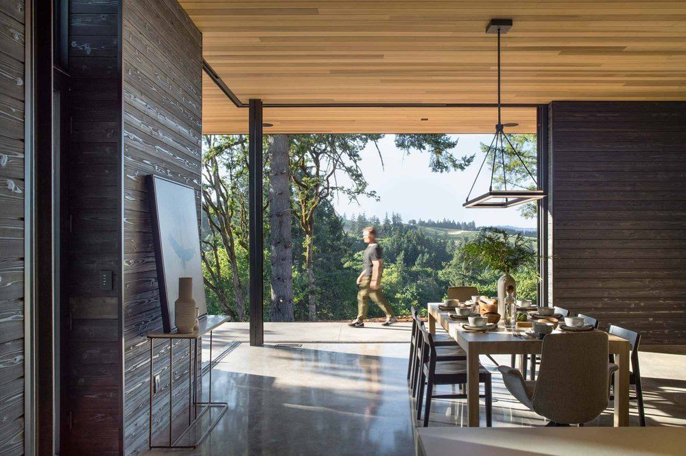 A man is walking through a dining room with a table and chairs.