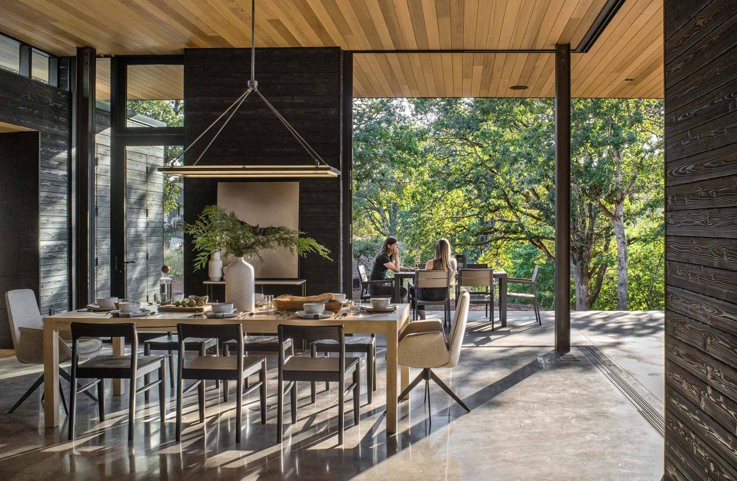 A dining room with a table and chairs and a view of the trees.