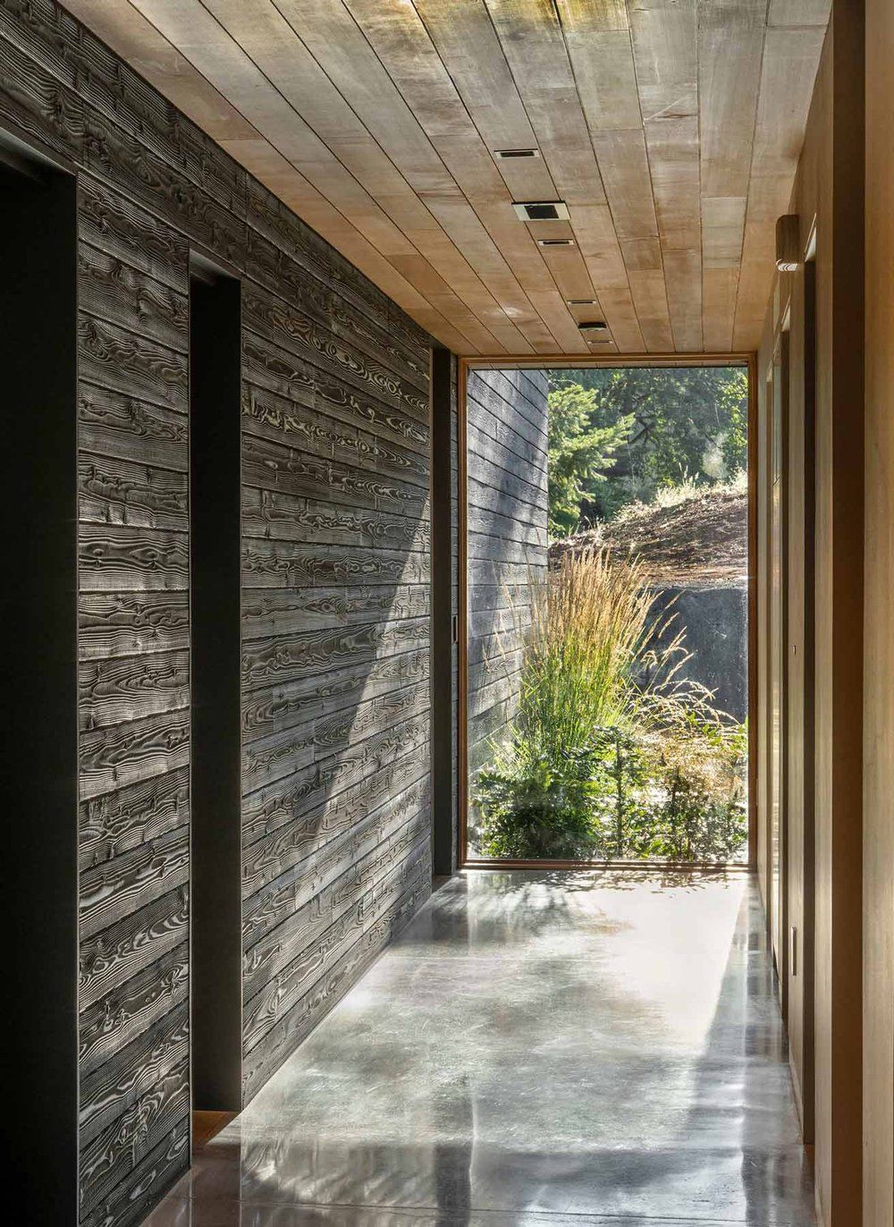 A long hallway with a large window and a brick wall.
