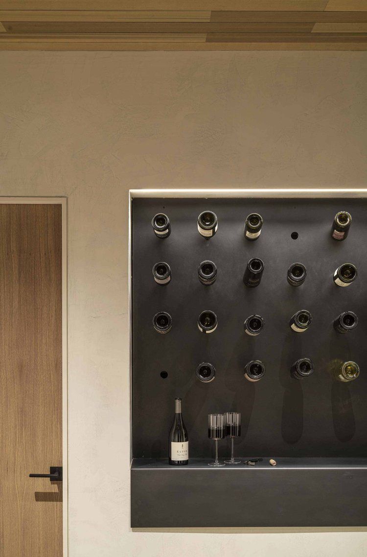 A bottle of wine is sitting on a shelf next to a wall with wine bottles on it.