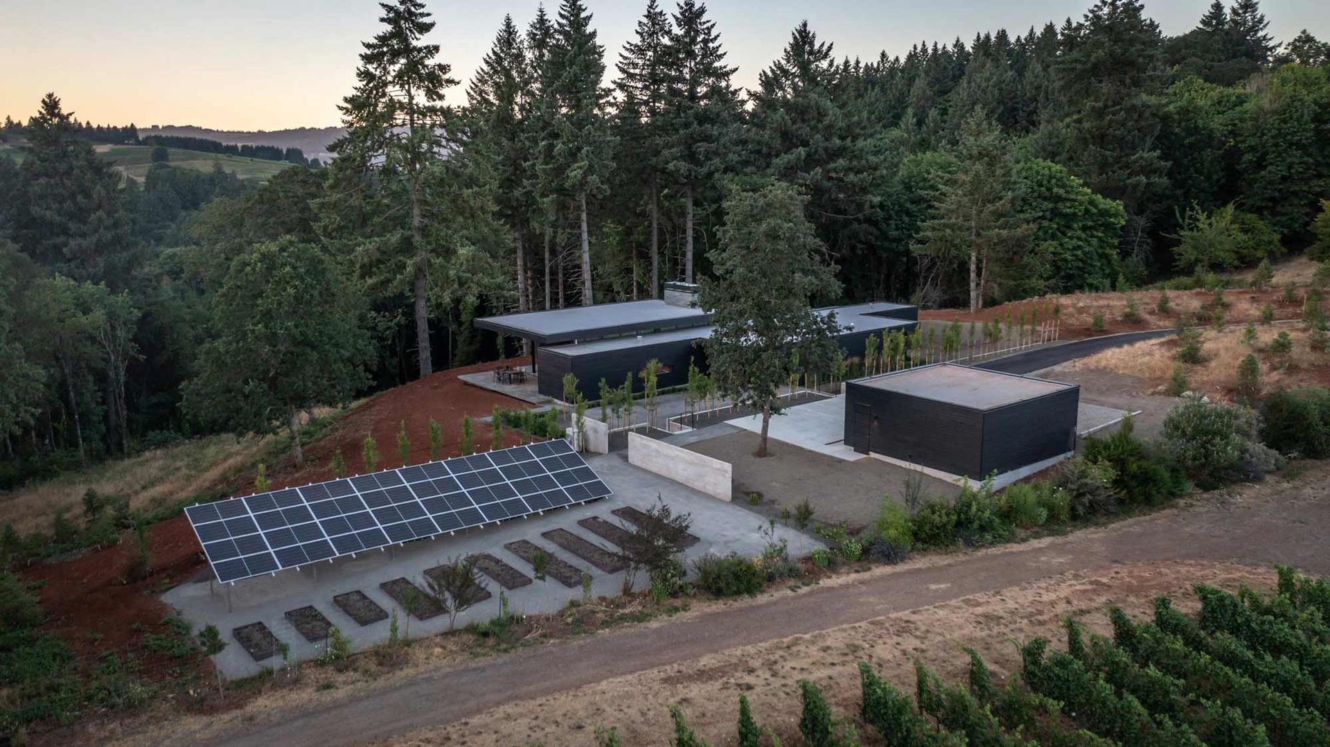 An aerial view of a house in the middle of a forest surrounded by trees.