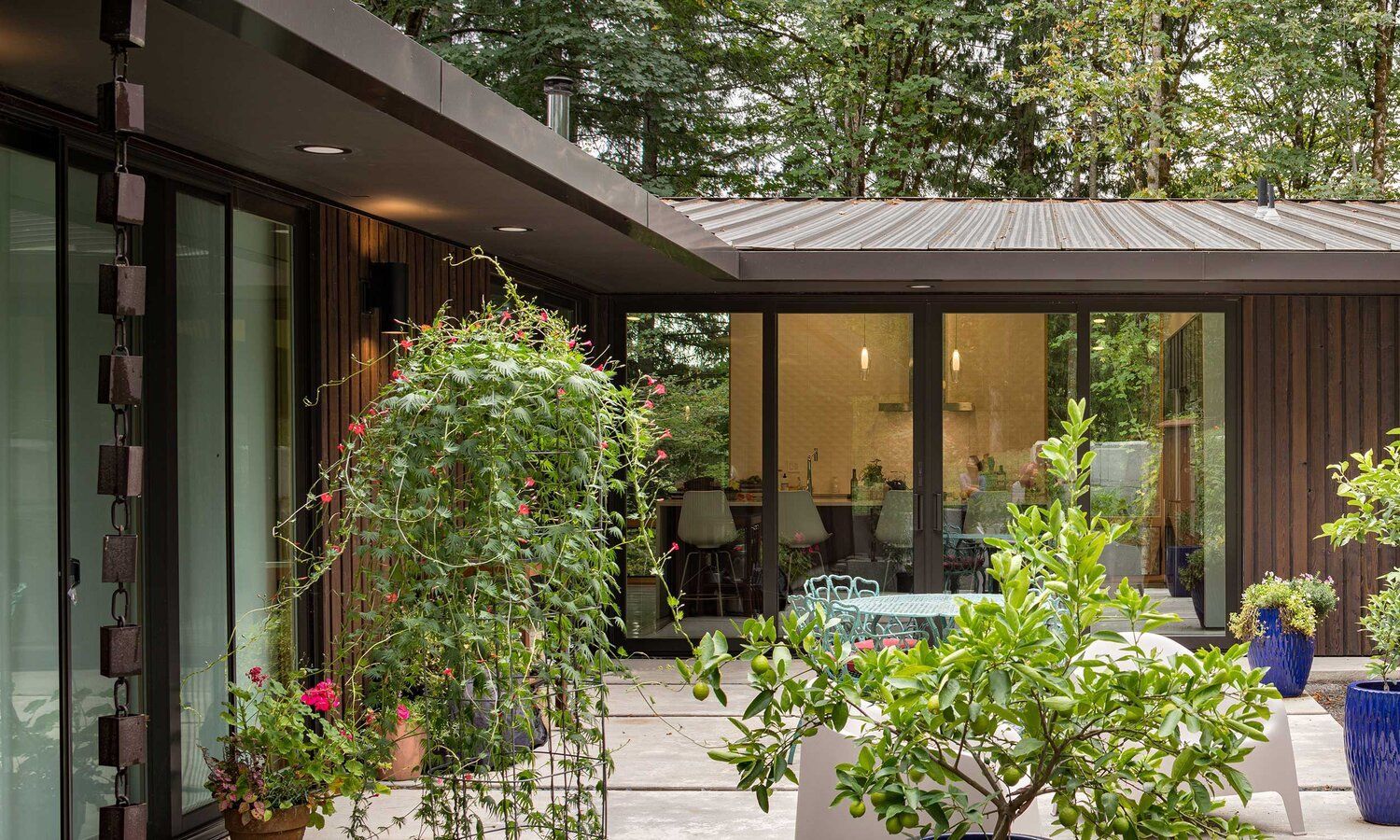 A house with a lot of windows and potted plants in front of it.