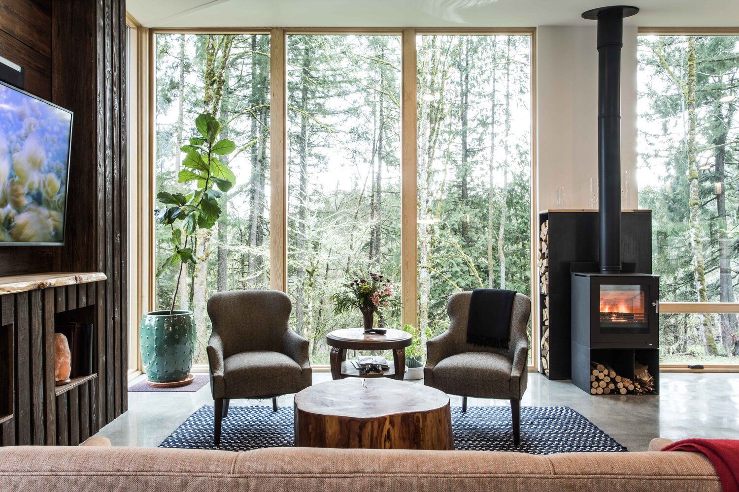 A living room with a couch , chairs , a table and a fireplace.