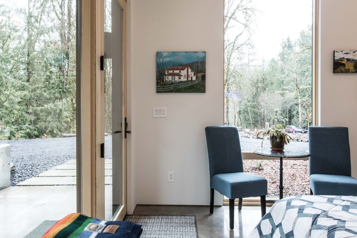 A bedroom with a bed , chairs and a painting on the wall.