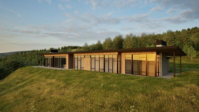 A large house is sitting on top of a grassy hill surrounded by trees.