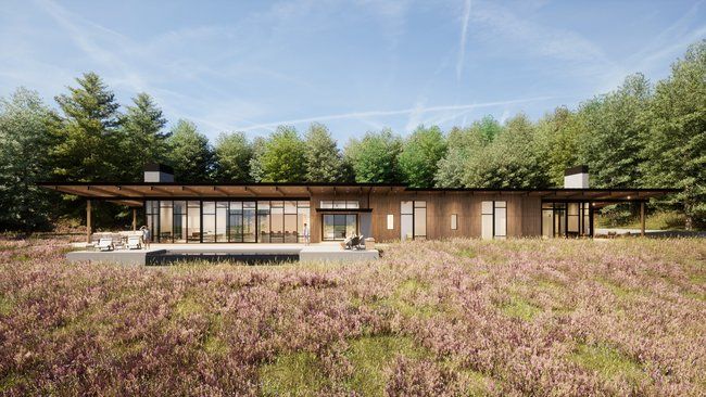 A large house is sitting in the middle of a field surrounded by trees.