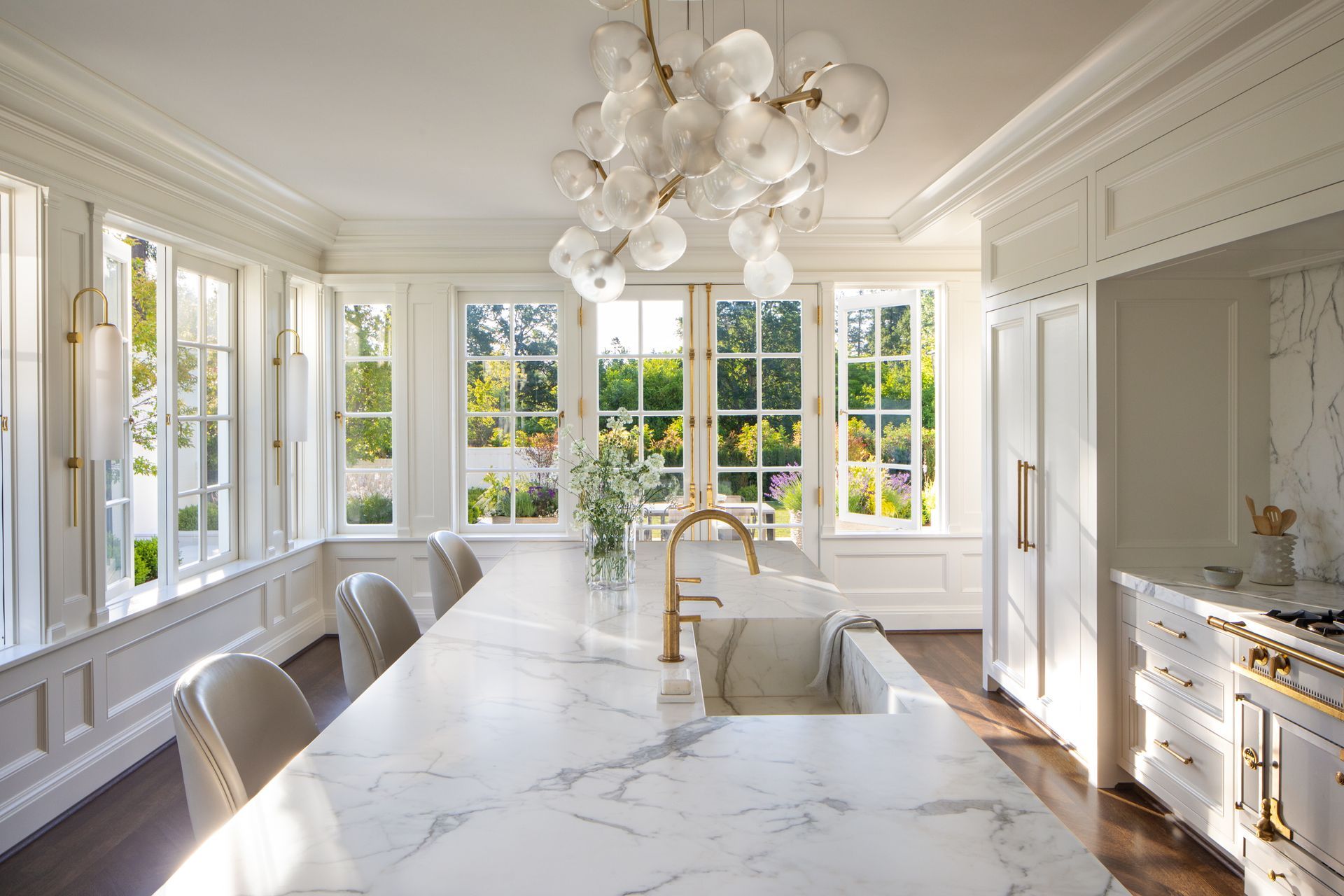 A kitchen with white cabinets, a large island, a sink, and a chandelier.