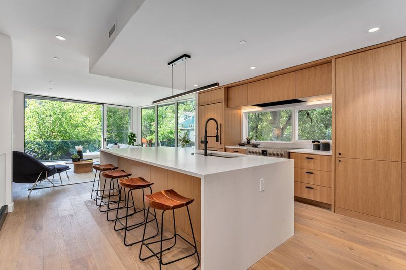 A kitchen with a large island and stools in it.