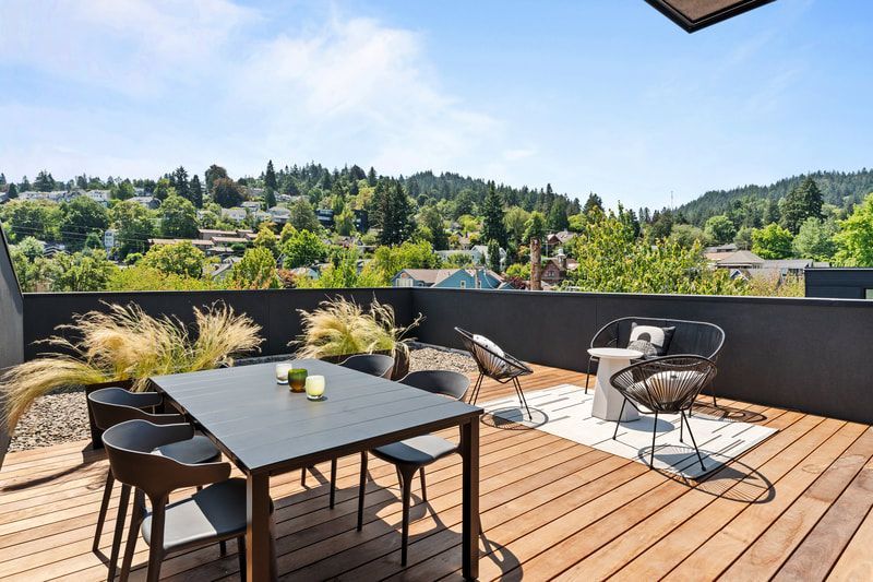 A rooftop deck with a table and chairs and a view of a city.