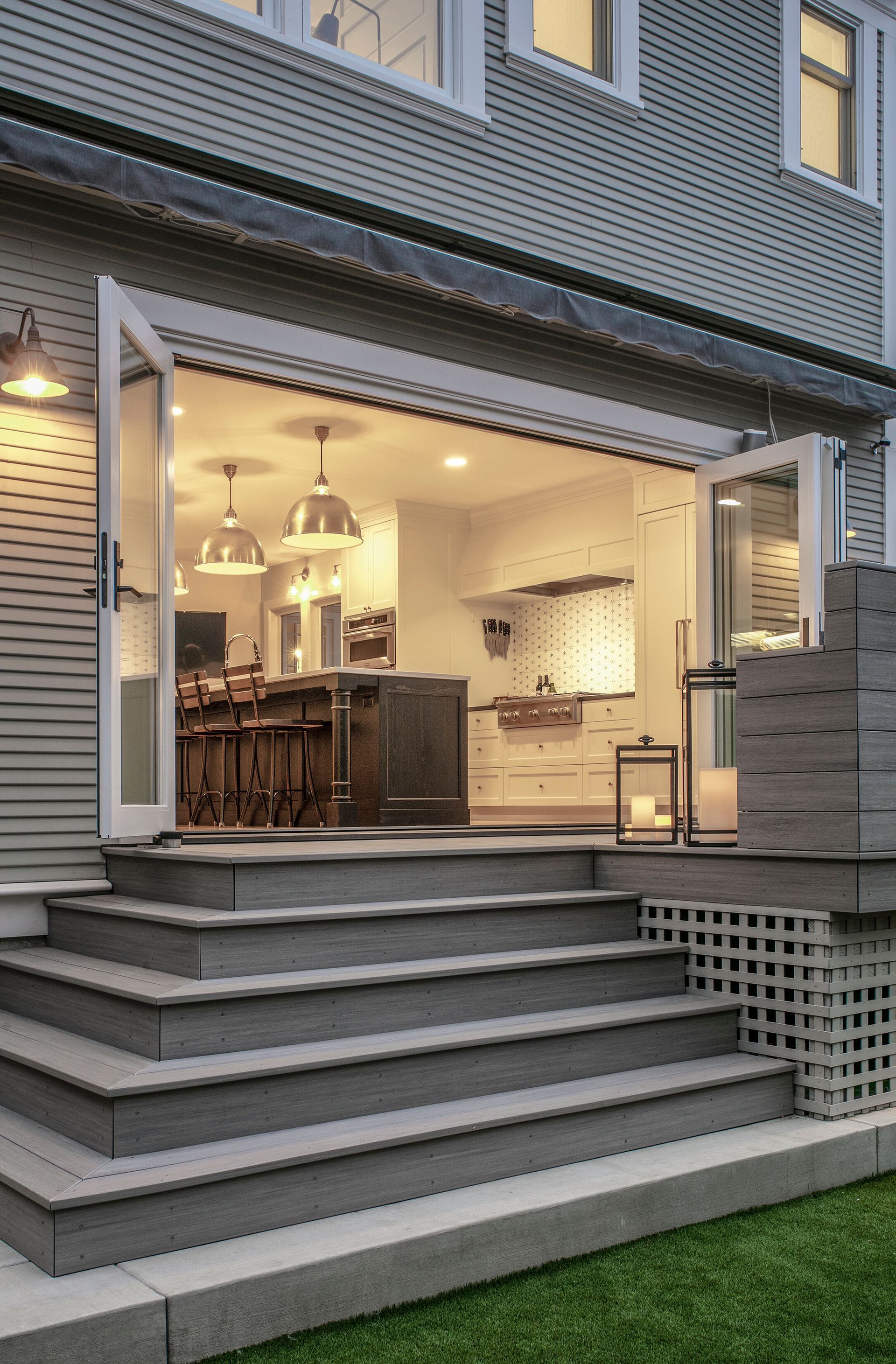 The back of a house with stairs leading up to it and a sliding glass door.