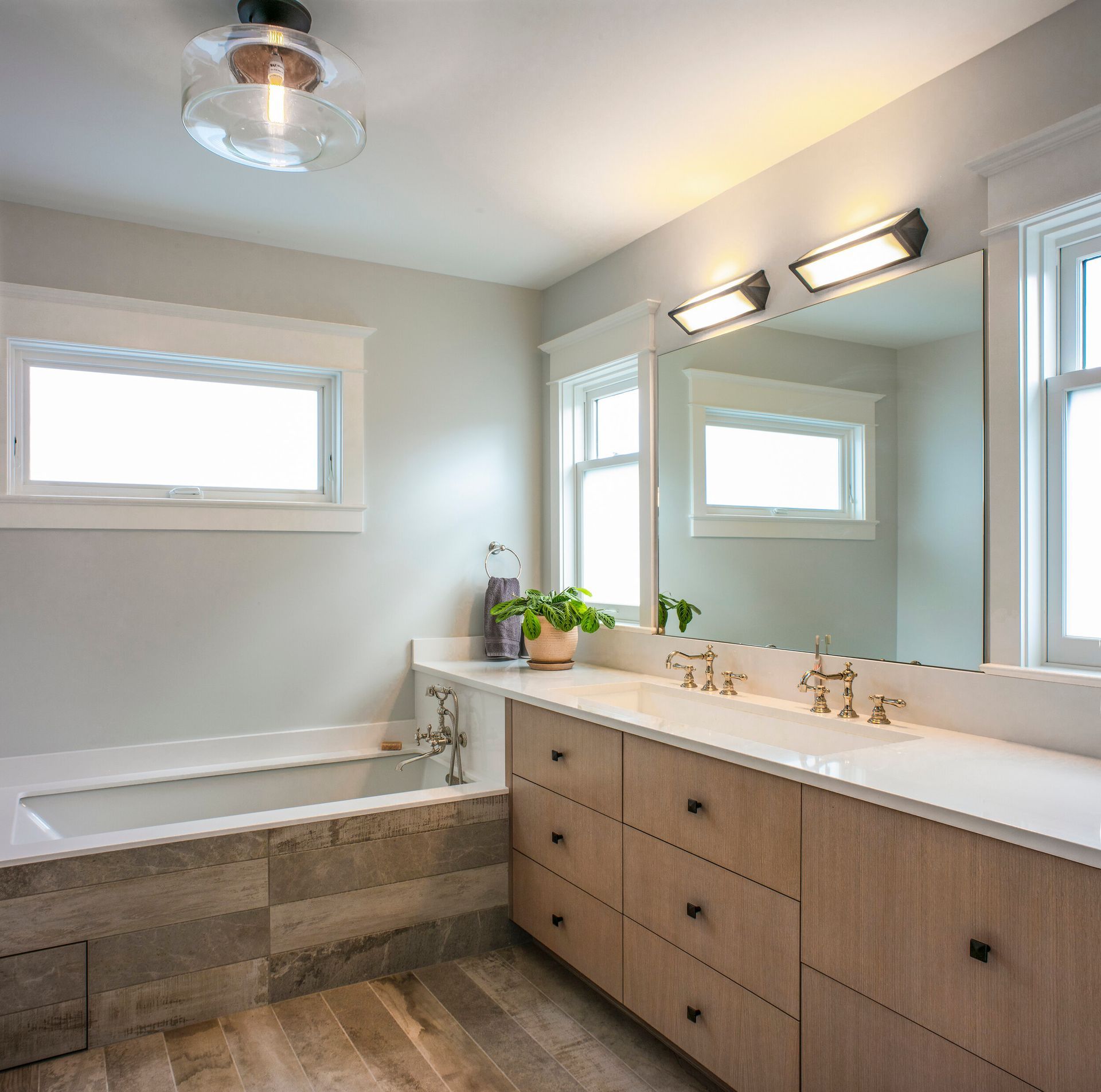 A bathroom with two sinks , a tub and a mirror