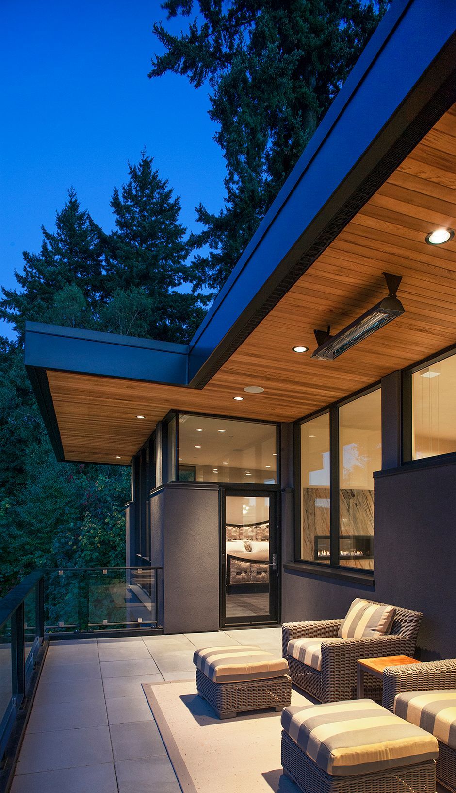 A modern house with a patio with chairs and ottomans