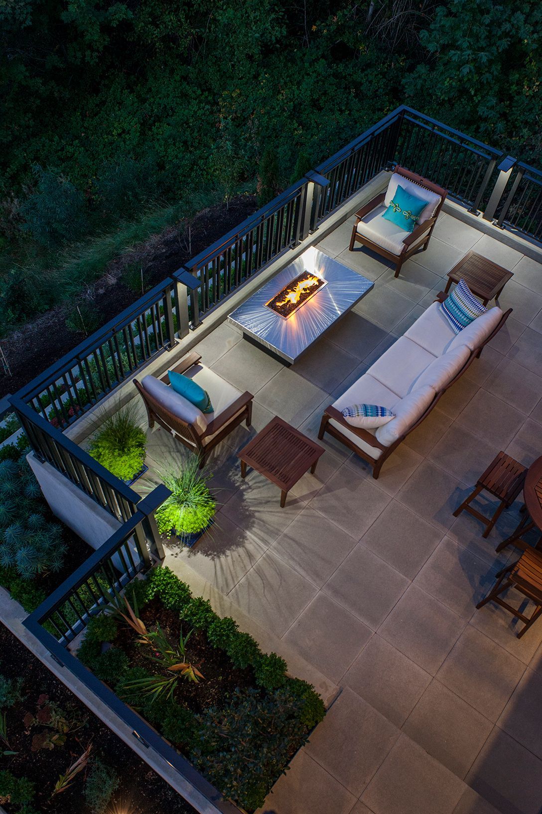 An aerial view of a patio with furniture and a fire pit at night.