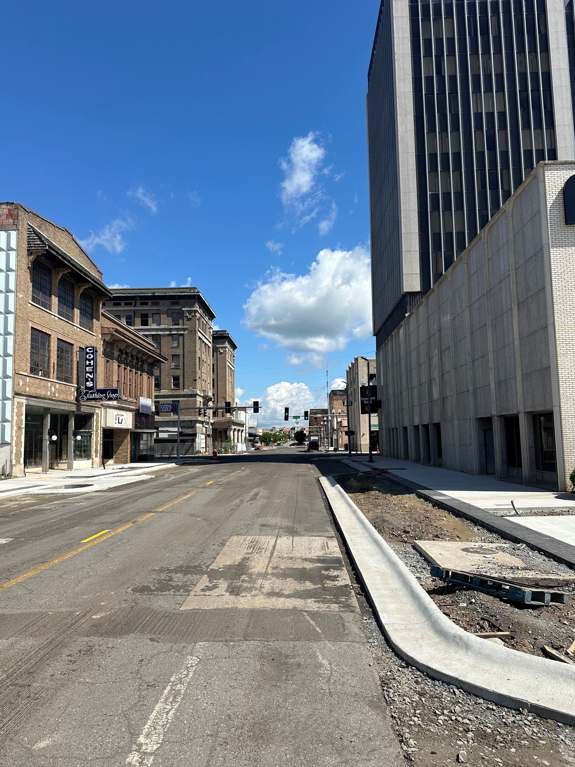 Downtown street view with tall buildings, road under construction, clear blue sky.
