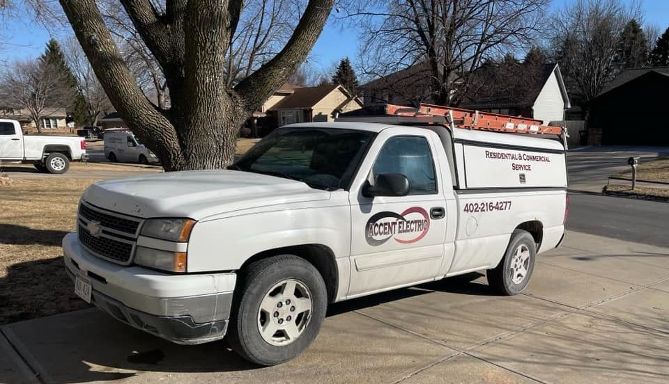 A white truck is parked in a driveway next to a tree