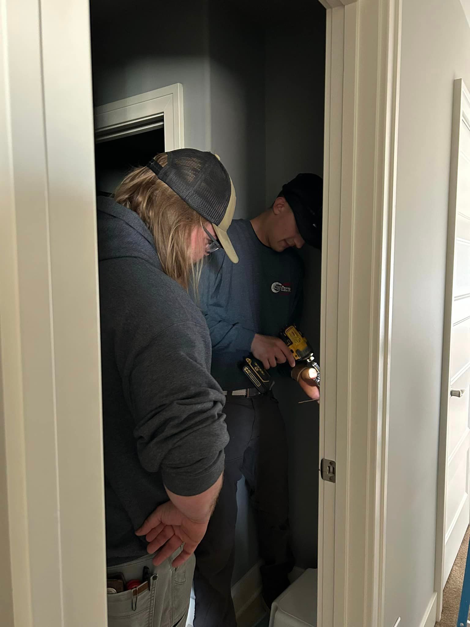 Two men are working on an electrical wiring near the door