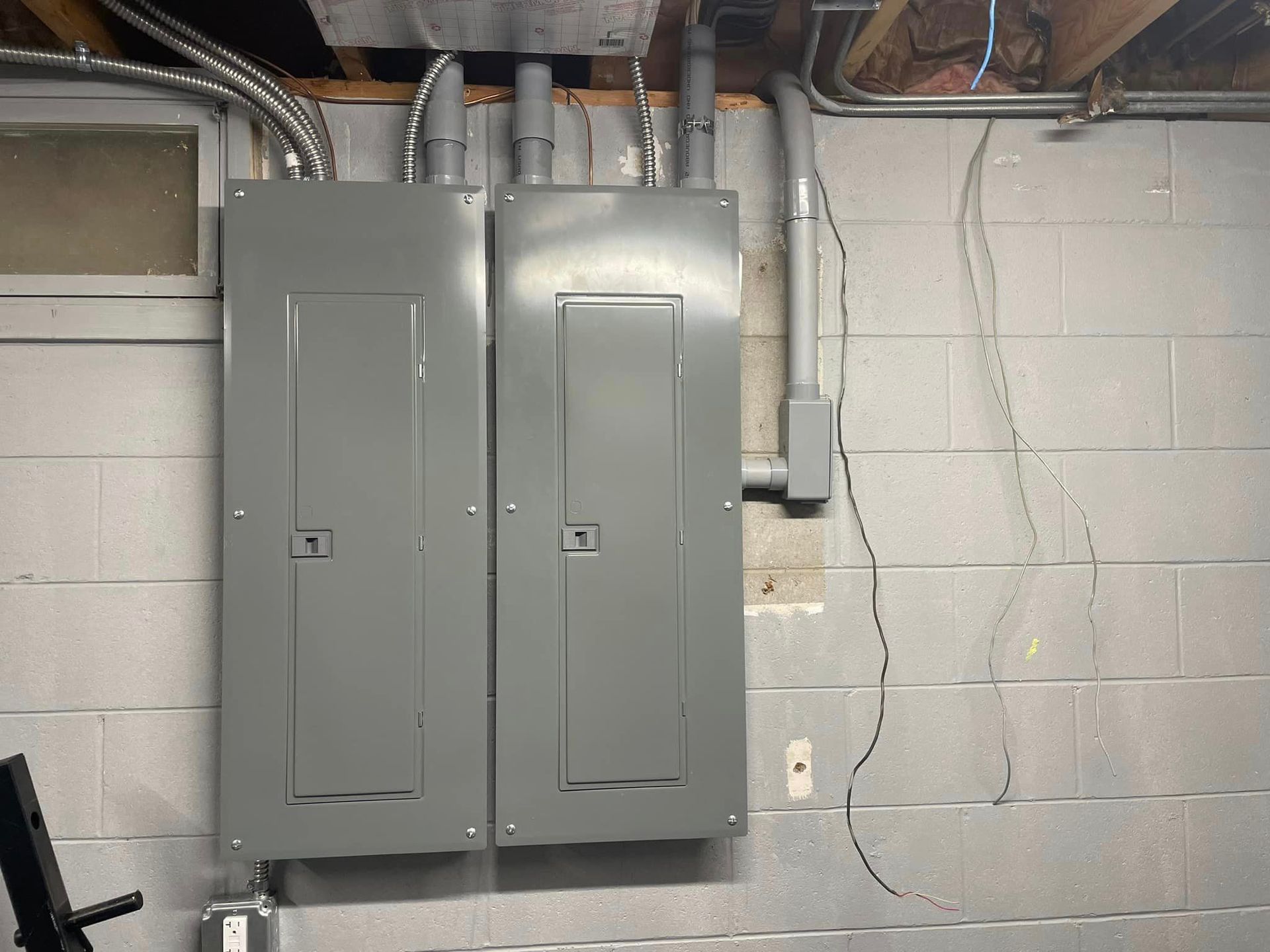 A gray electrical box is hanging on a white brick wall