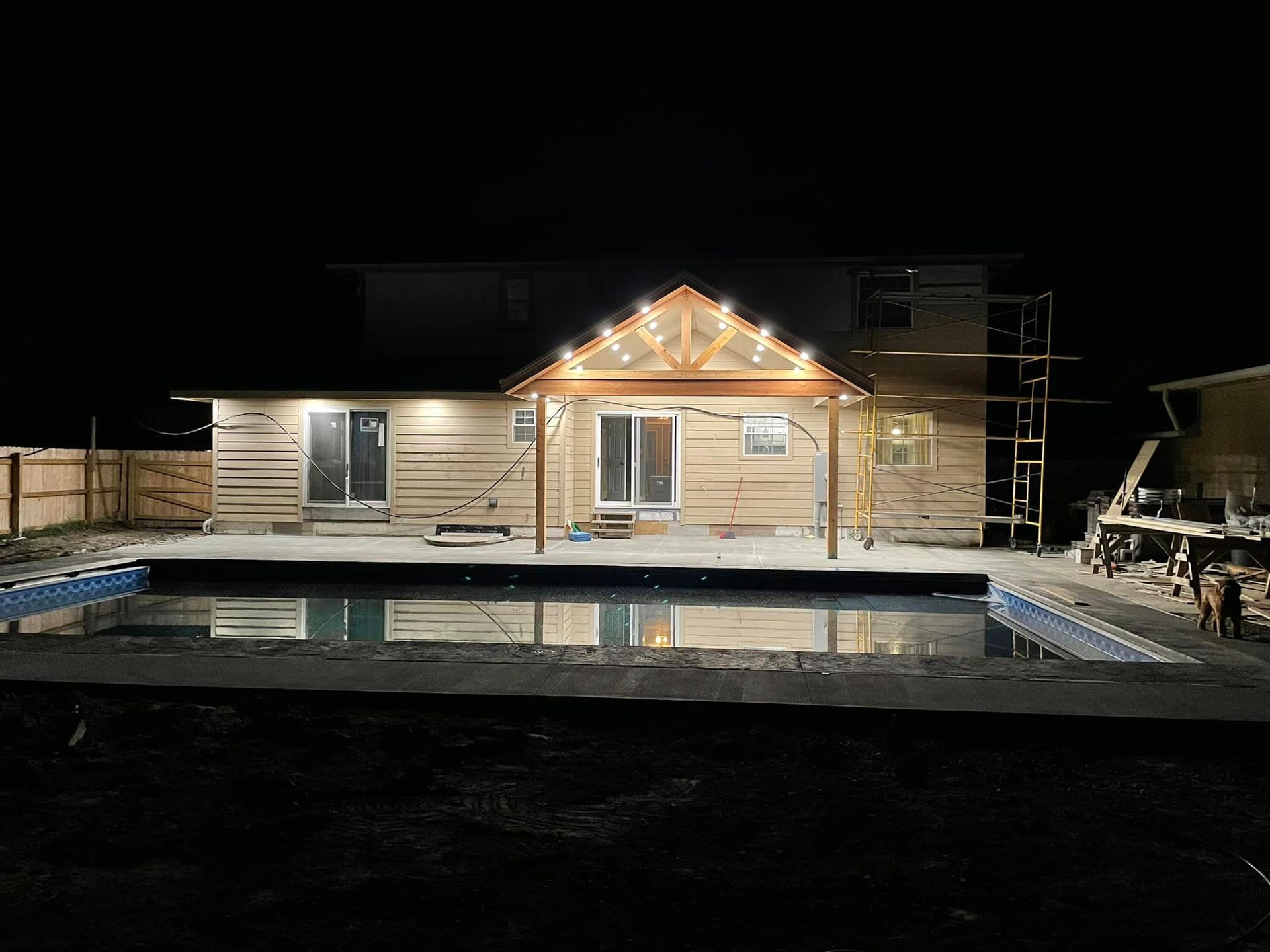 A house with a swimming pool in front of it at night