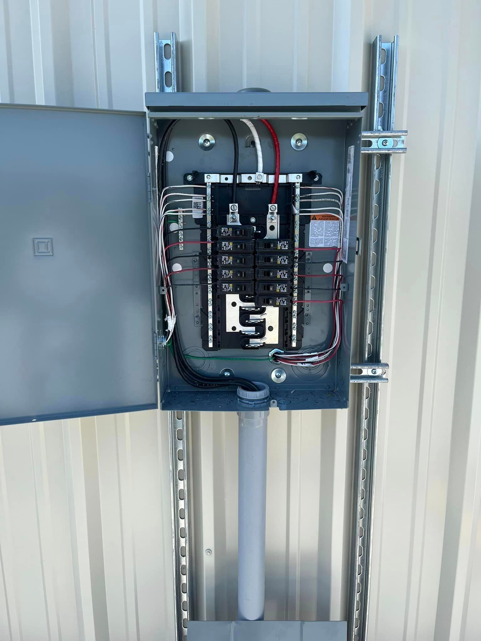 A electrical box is hanging on the side of a building