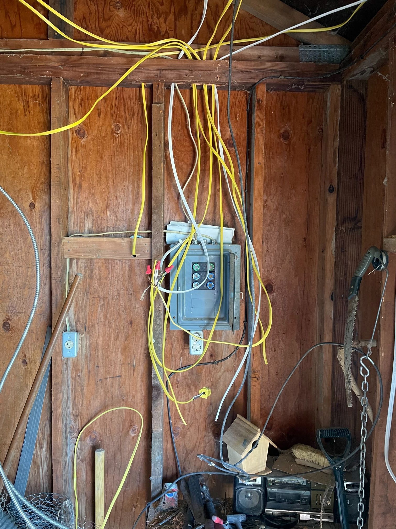 A messy room with a lot of wires hanging from the ceiling
