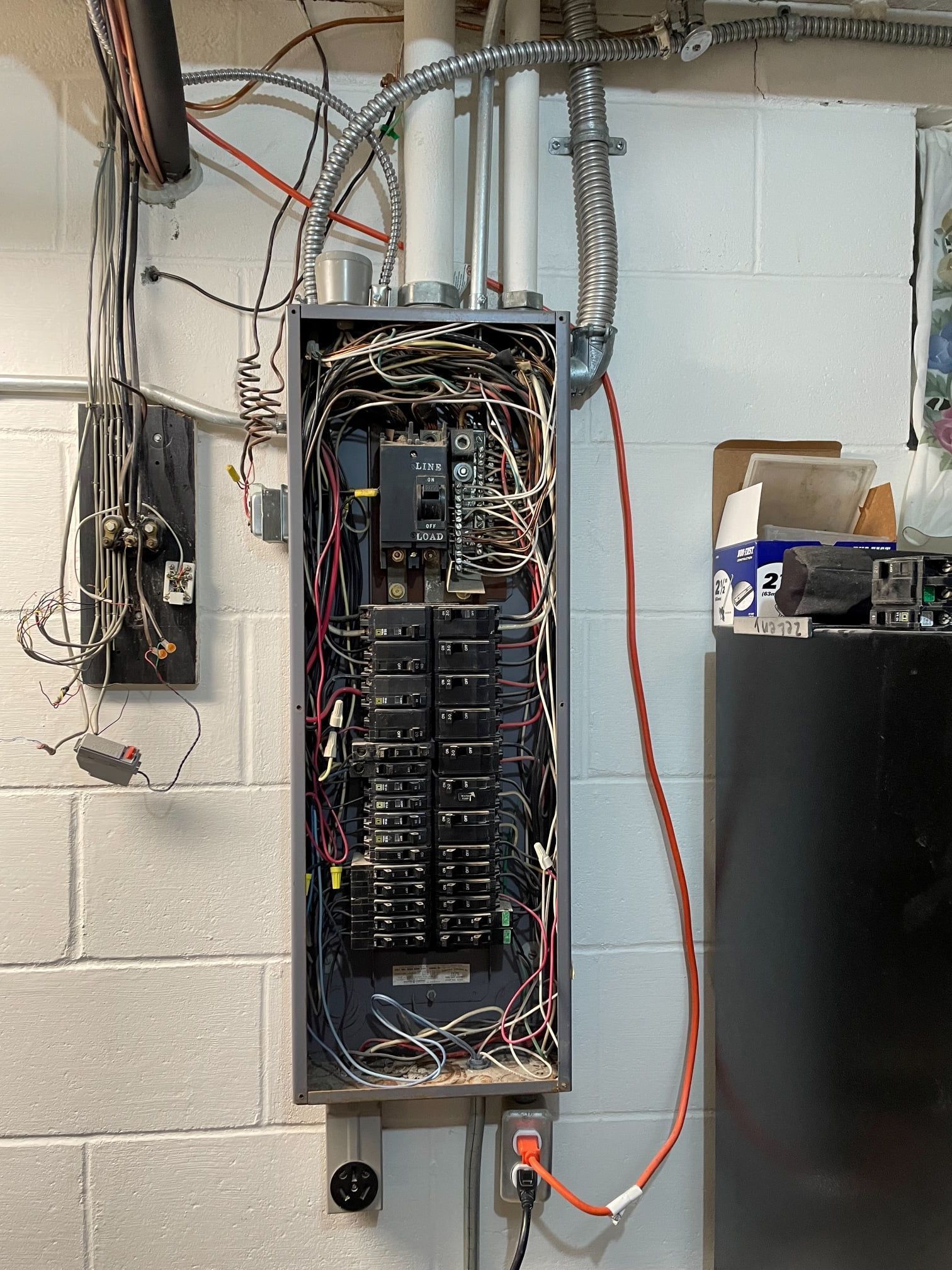 An electrical box is hanging on a brick wall