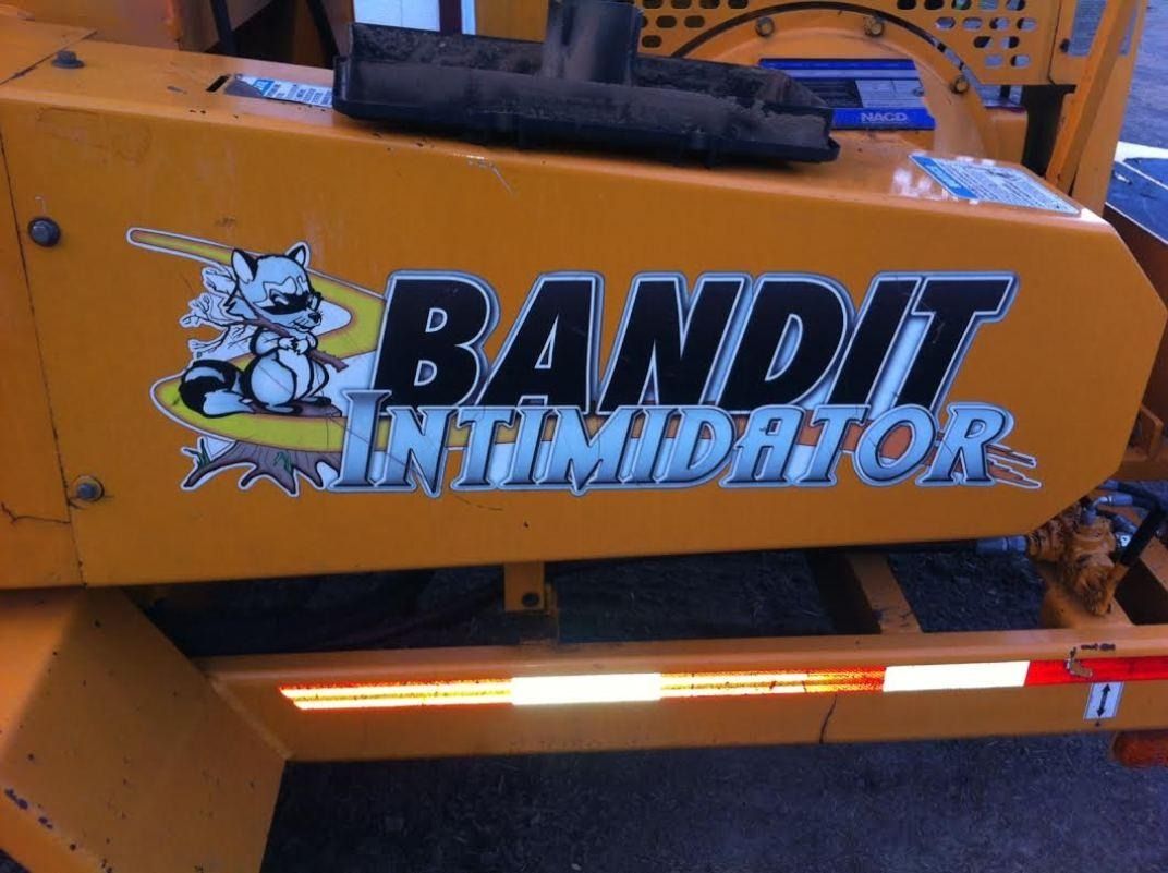 Yellow Bandit Intimidator stump grinder with logo on the side, reflective tape below.