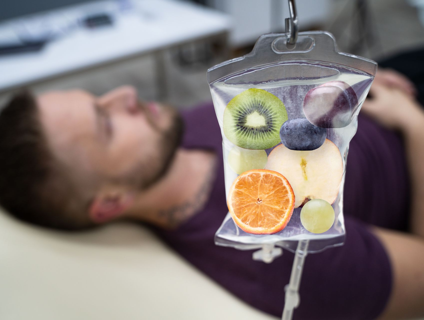 IV bag with fruits hanging above a man lying down, possibly receiving a vitamin drip at a clinic.