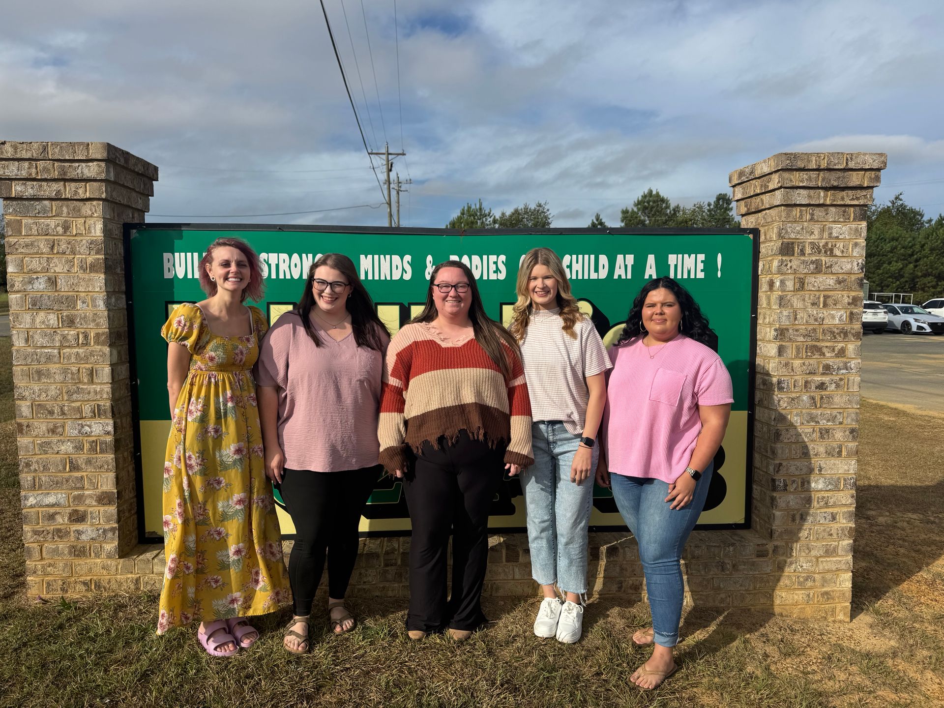 Five people standing in front of a school sign.