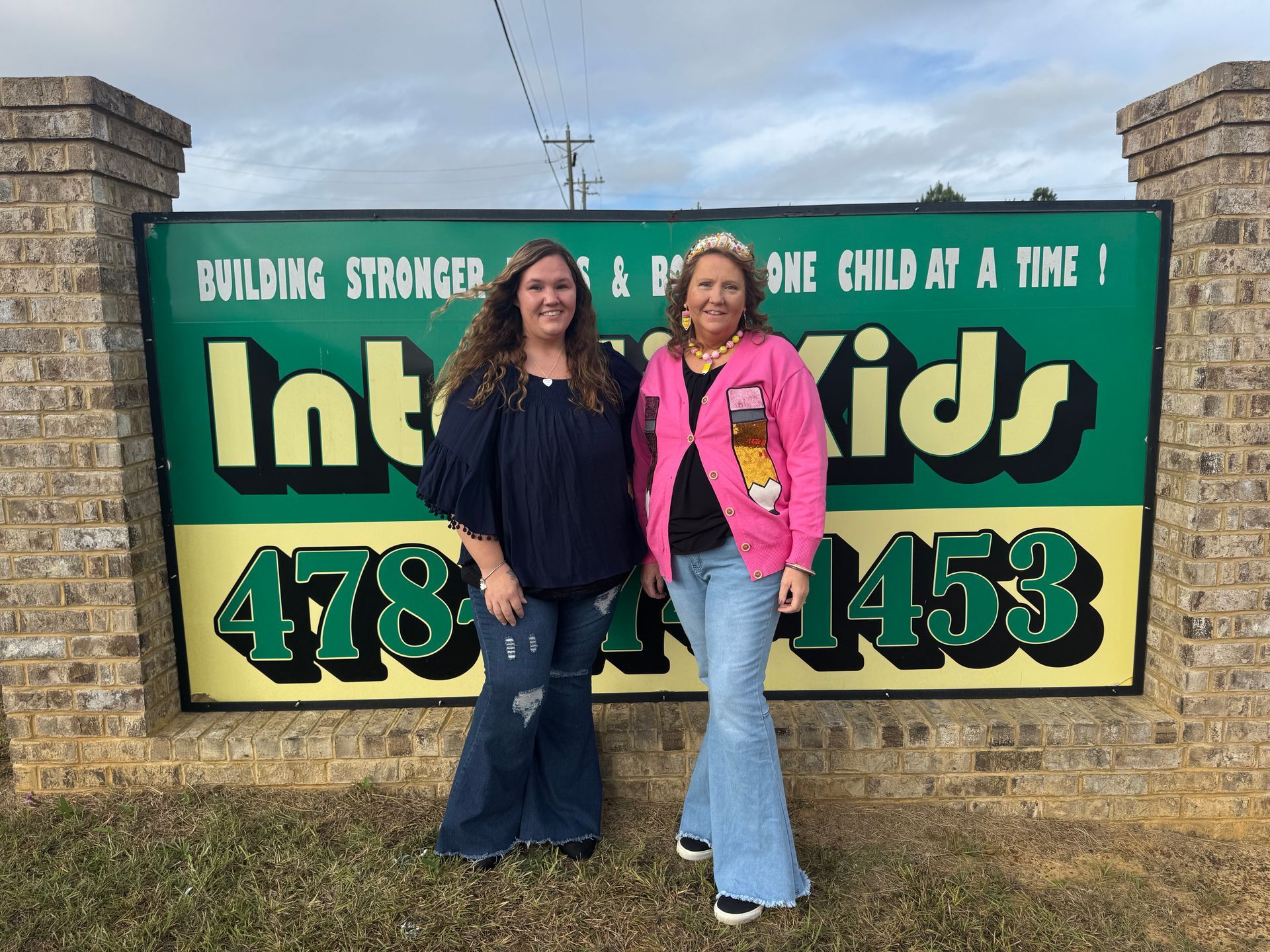 Two women standing in front of an sign.