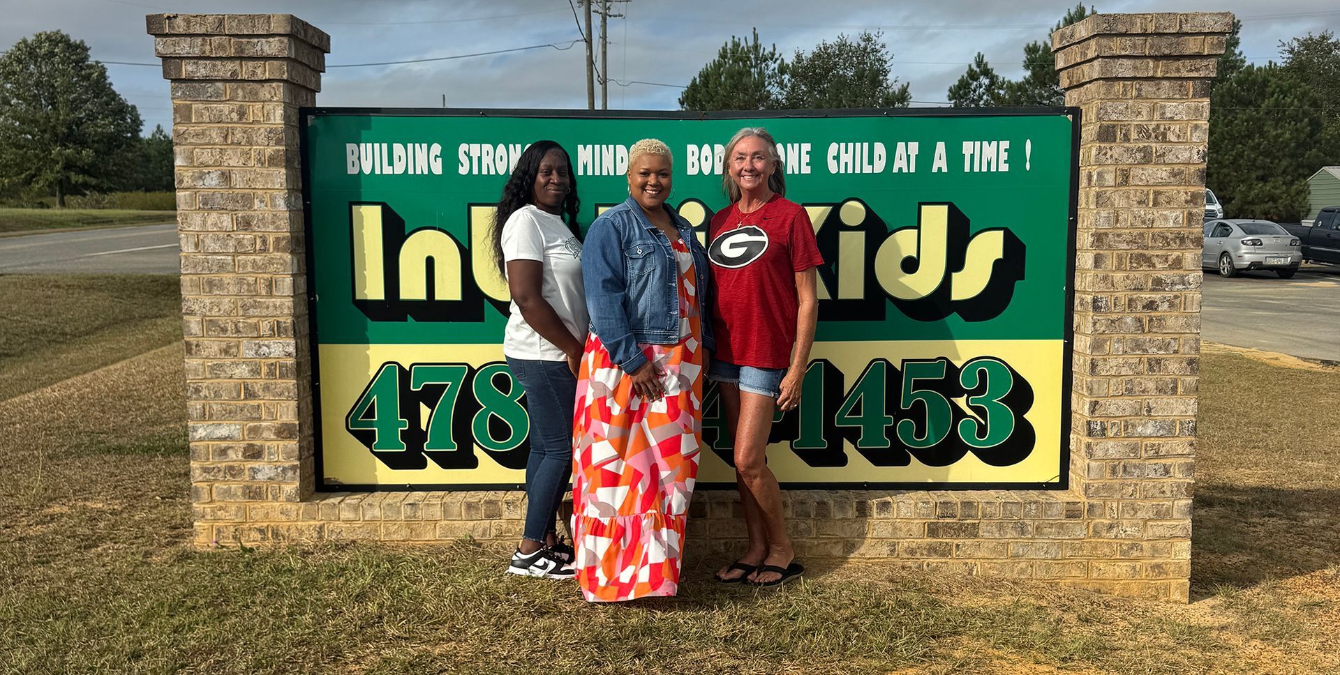 Three people standing in front of a  sign.