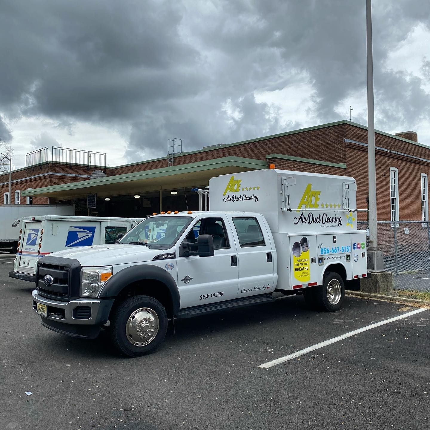 A white truck is parked in front of a brick building.