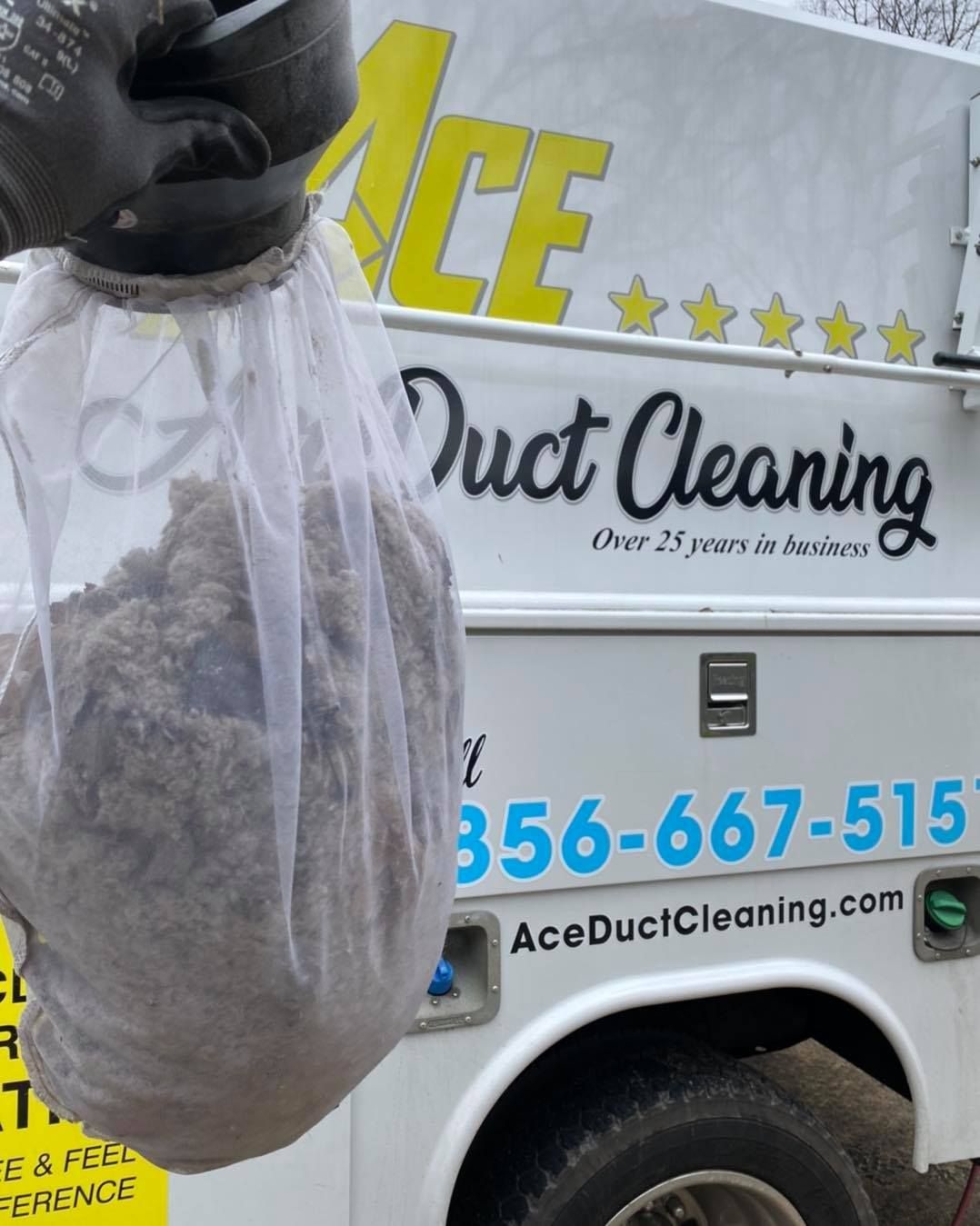 An ace duct cleaning truck with a bag of dirt on the back