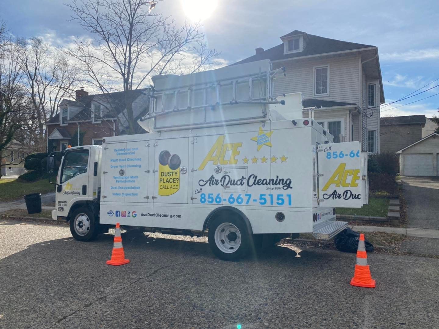An air duct cleaning truck is parked in front of a house.