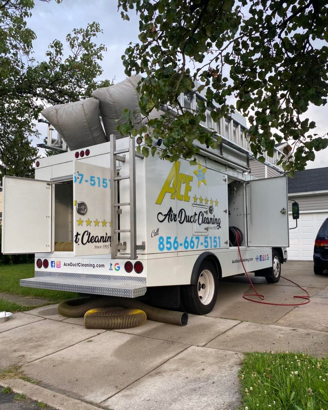 A white truck with the doors open is parked in front of a house.