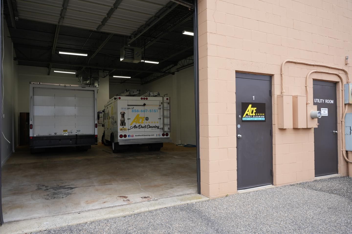 Two vans are parked in a garage with the door open.