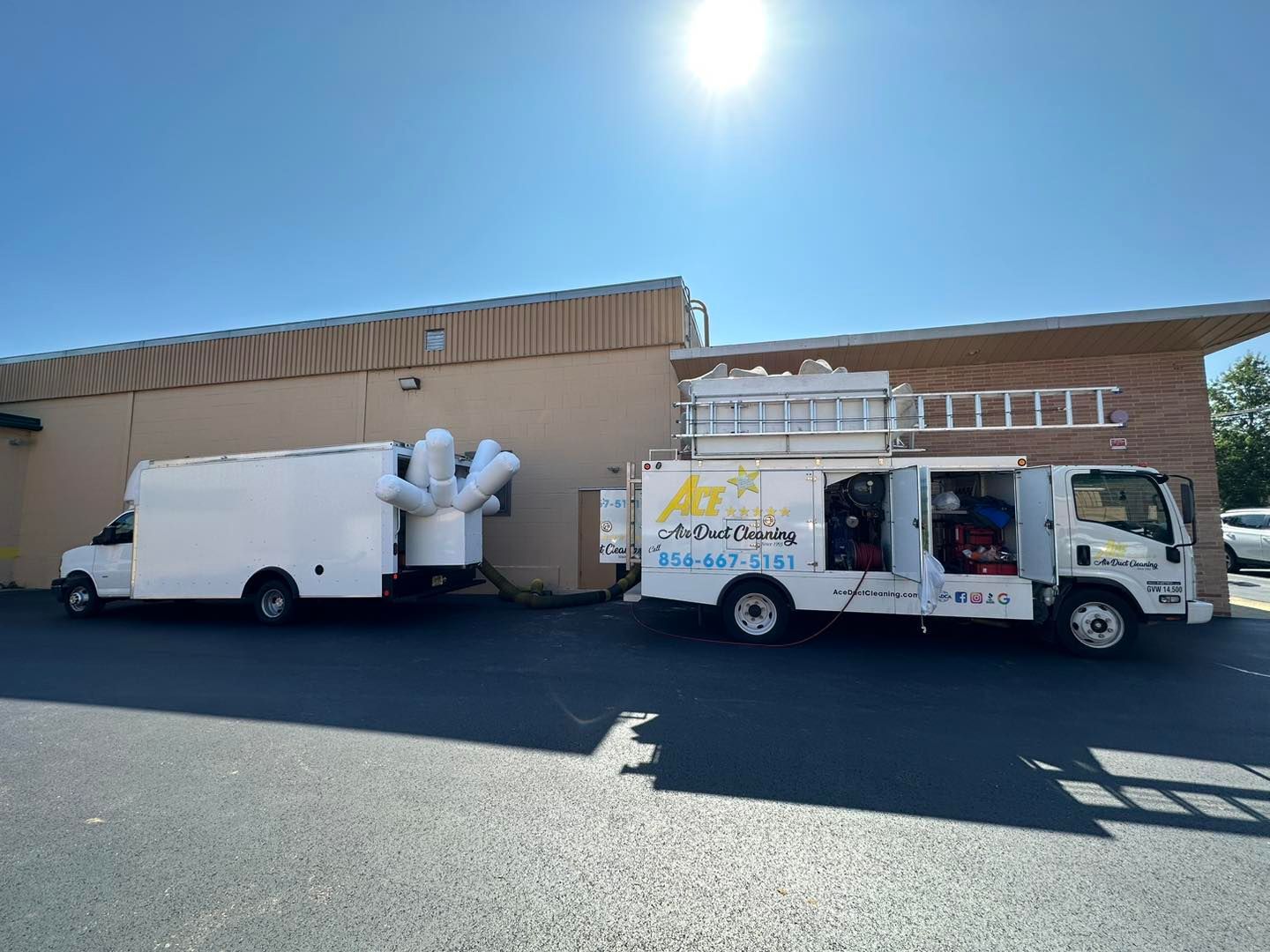 Two white vans are parked in front of a building.