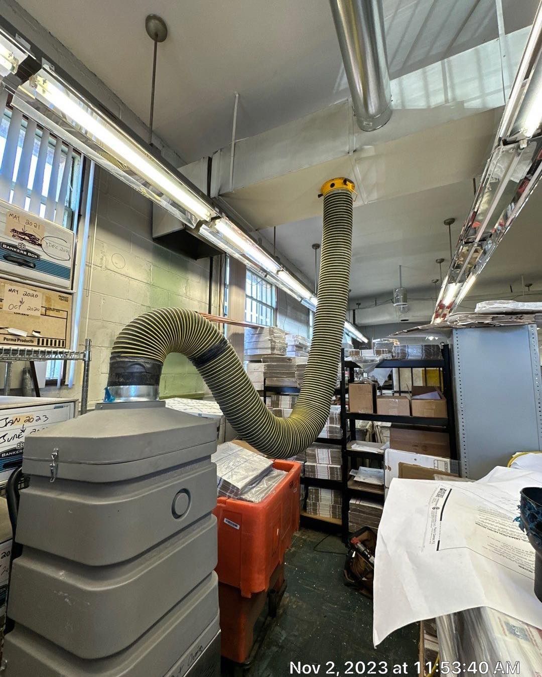 A hose is hanging from the ceiling of a room in a factory.