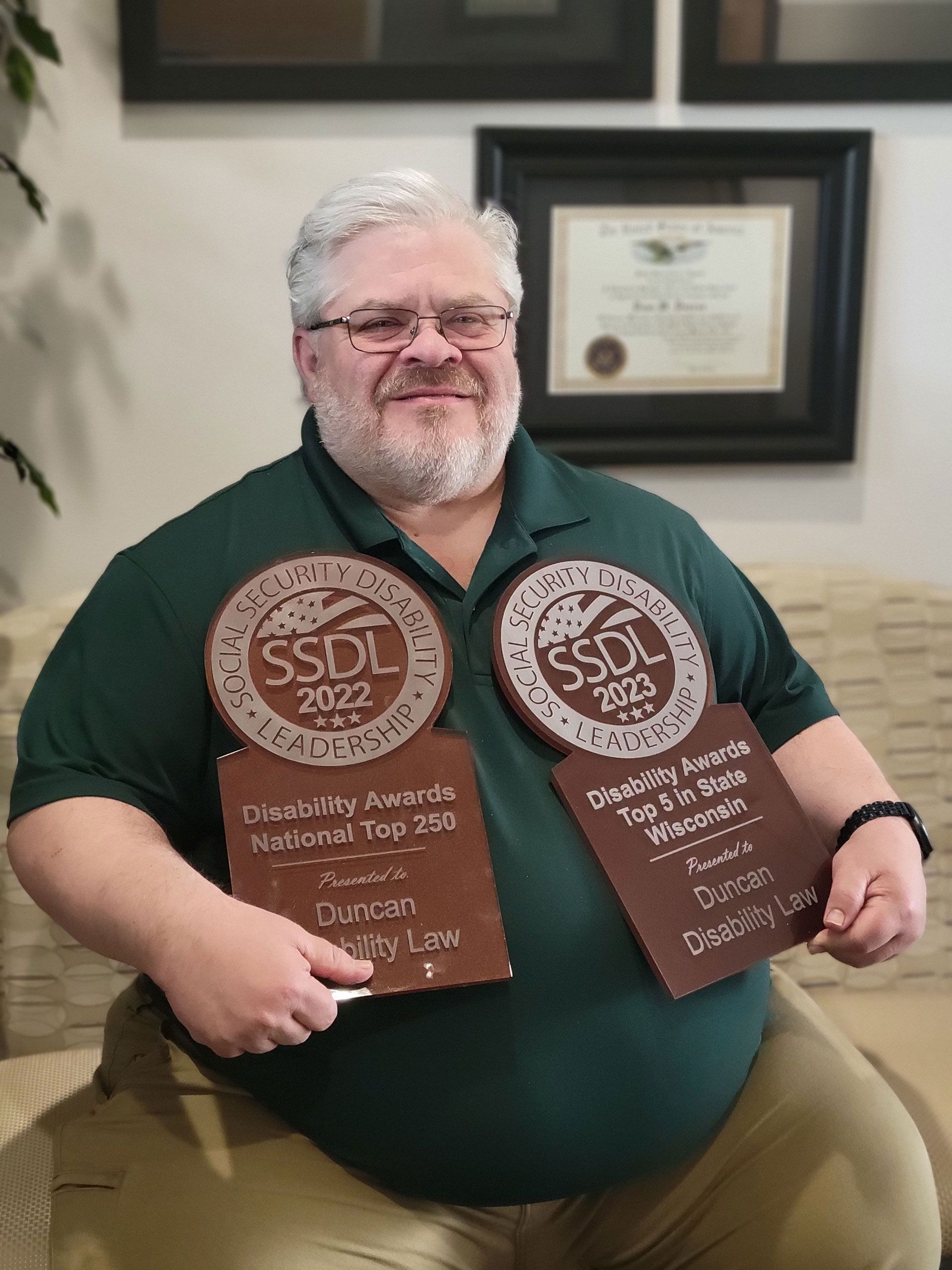 A man in a green shirt is holding two plaques